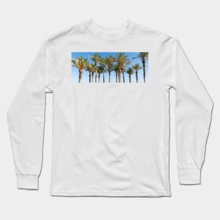 Row of tropical feeling palm trees against blue sky with luch green fronds. Long Sleeve T-Shirt